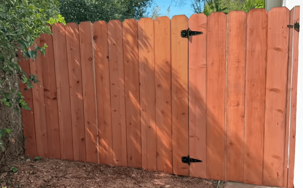 Finished cedar privacy fence with a gate and black strap hinges